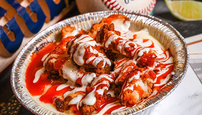 Crispy chicken tenders with ranch and hot sauce over mac & cheese—perfect bar comfort food.
