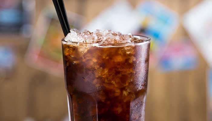 A glass of iced cola with a black straw, perfect alongside chicken wings at the bar.