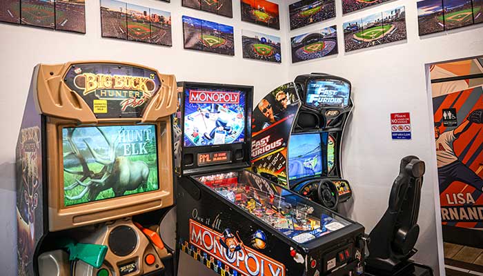 Arcade room with Big Buck Hunter, racing games, baseball photos, and chicken wings from the bar.